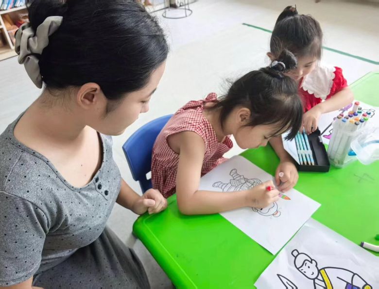 圖為實(shí)踐隊(duì)隊(duì)員在和小朋友涂色 閆藝凡供圖